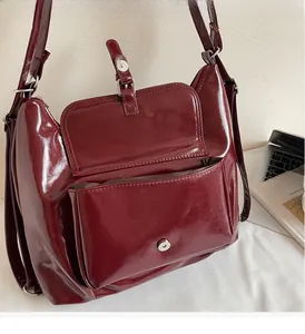 Close-up of deep red glossy patent leather shoulder bag with metallic buckle detail