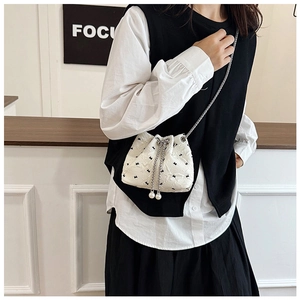 Detail of mini bucket bag featuring black embroidery, drawstring and pearl charms