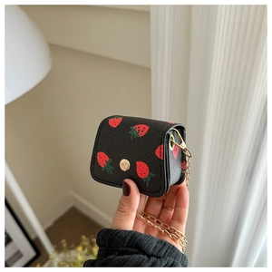 Close-up of black leather mini wallet with strawberry print and gold snap button