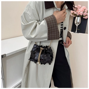 Détail du sac seau noir à paillettes avec cordon en chaîne dorée et perles sur un modèle