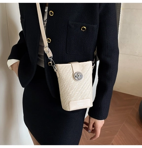 Detail of cream-white woven texture crossbody bag with vintage round metal buckle closure