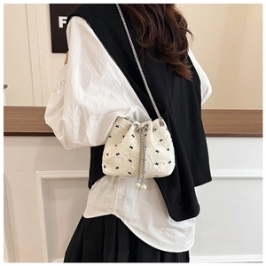 Detail of a creamy white bucket bag with drawstring pearls and silver chain strap
