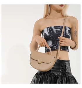 Detail of beige crescent shoulder bag with golden metal buckle on a white background