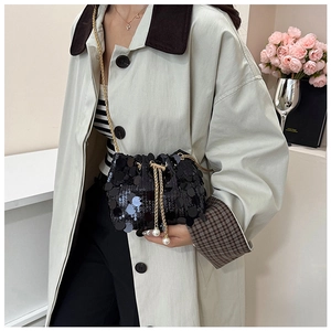 Detail of black sequined bucket bag with gold chain drawstring and pearl accents