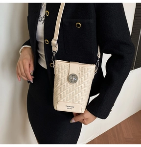 Close-up of cream woven texture crossbody bag with silver round twist lock detail