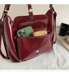 Detail of burgundy glossy leather bag showing external pocket with magnetic closure