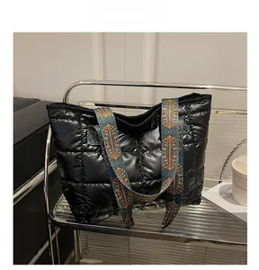 Detail of black quilted puffer tote with colorful ethnic geometric woven strap
