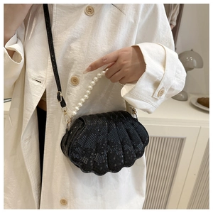 Detail of black shell bag with snake pattern texture and elegant pearl handle strap