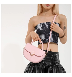 Detailed view of a pink saddle bag with golden circular magnetic closure and top handle