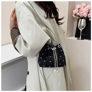 Detail of black bucket bag with white bow embroidery, pearl drawstring and silver chain