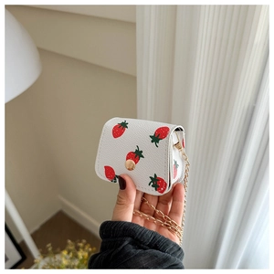 Detail of mini strawberry print white leather crossbody bag with gold button and chain