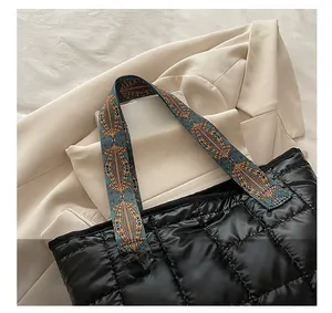 Detail of black quilted puffer bag with colorful geometric pattern handles on a blazer