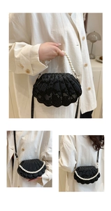 Close-up of black snake pattern shell handbag featuring elegant white pearl handle
