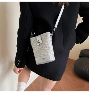 Detail of silver woven crossbody bag featuring a metallic texture and twist-lock closure