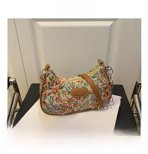 Détail de broderie florale vintage, garniture cuir marron et chaîne argentée du sac