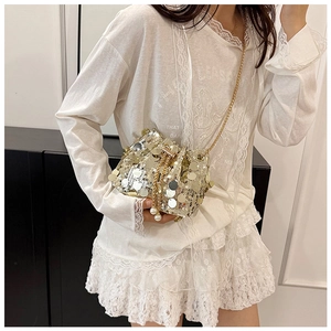 Detail of sequin bucket bag featuring pearl drawstring closure and gold chain strap