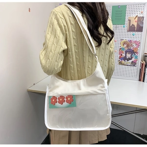 White nylon ita bag with large clear PVC pocket shown on shoulder in a studio setting