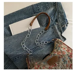 Détail du sac à fleurs avec poignée en cuir marron et bandoulière en chaîne métal