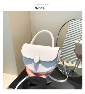 Detail of white leather half-moon bag with metallic clasp and curved handle held by hand