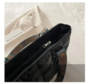 Detail of silver zipper closure on black quilted tote with ethnic print webbing strap