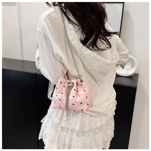 Pink quilted bucket bag with bow print and pearl drawstring detail on model