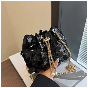 Détail d'un sac seau noir à paillettes avec bandoulière dorée et accents perlés