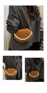 Detail of a brown shell-shaped crossbody bag featuring snakeskin texture and pearl handle