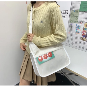Detailed view of white crossbody ita bag with clear window featuring flower card accessory
