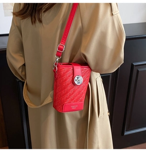 Detail of red woven mini crossbody bag with silver twist lock and slim shoulder strap