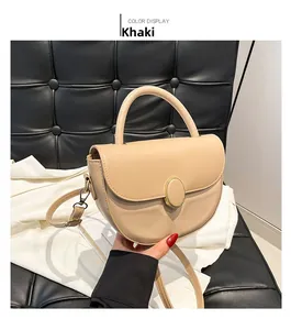 Detail of khaki saddle bag showing matte leather texture and gold oval metal buckle
