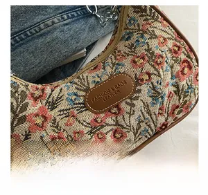 Gros plan sur la broderie florale avec écusson en cuir et détails de chaîne en métal