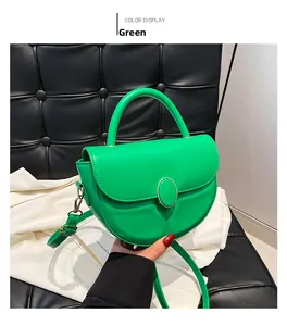 Detail of green semi-circular saddle bag featuring polished leather and metal buckle