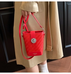 Detail of red woven texture bucket bag with silver twist lock and gold logo lettering