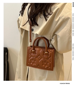 Detailed side view of brown embossed crossbody bag worn with a chic autumn trench coat