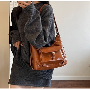 Detail of caramel brown faux leather handbag showing silver buckle and glossy texture