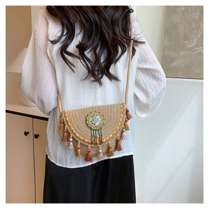 Detail of bohemian straw crossbody bag with colorful tassels and ethnic embroidery decoration