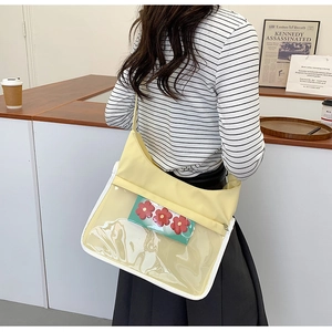 Detailed view of yellow fabric and clear PVC messenger bag with green floral pouch
