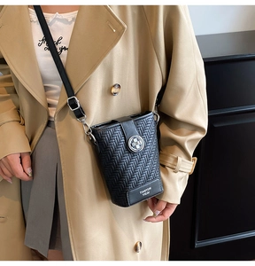 Close-up of black woven leather bucket bag with metallic logo and chain strap