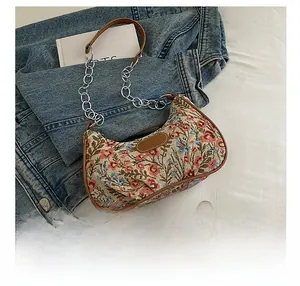Vue détaillée du tissu jacquard floral avec bordure en cuir brun et chaîne argentée
