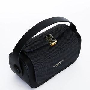 Detail of black leather cylindrical handbag featuring a gold scalloped metal buckle