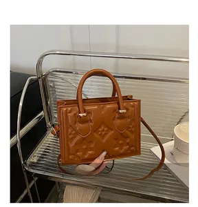 Detail of a brown vintage leather handbag with embossed floral patterns and gold hardware
