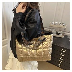 Model wearing a gold quilted puffer tote bag with a geometric print wide shoulder strap