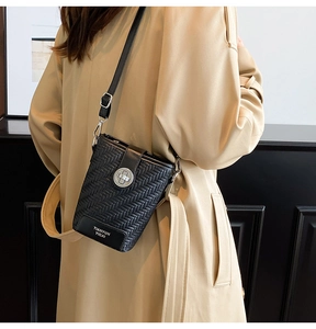 Detail of black woven crossbody bag with silver twist lock and slim leather shoulder strap