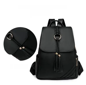 Detailed view of black pebbled leather backpack with metal ring and long tassel charm