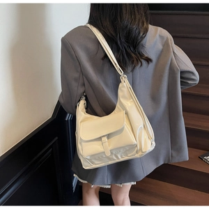 Detail view of cream white patent leather tote bag with silver buckle pocket on a model