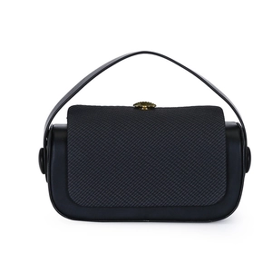 Detail of black leather handbag with grey fabric panel and golden circular metal clasp