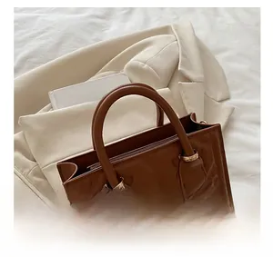 Close-up of brown embossed tote bag featuring gold hardware and premium texture