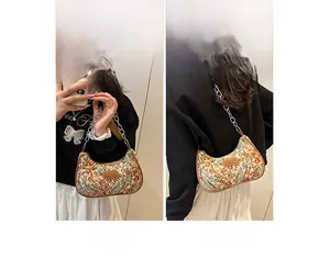Détail du sac croissant en toile florale avec chaîne en métal et bandoulière en cuir
