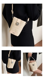 Detail of beige woven texture crossbody bucket bag with circular metal twist lock buckle