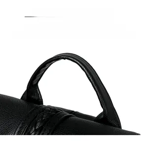 Detail of black pebbled leather handbag with rounded handle and woven texture accent